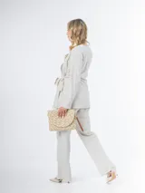 Conjunto de dos piezas confeccionado en lino color beige, compuesto por un pantalón de corte recto y un blazer cruzado con lazo ajustable en la cintura y escote en V.