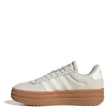Championes Adidas modelo VL Court Bold con diseño de plataforma alta. Presentan una capellada de cuero en tono gris claro con las icónicas tres tiras laterales y detalles de marca en dorado. Cuentan con suela de goma color caramelo y cierre mediante cordones.