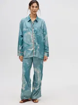 Camisa oversize de viscosa con diseño tie-dye en tonos celestes y blancos, manga larga, cuello camisero, cierre frontal con botones y un bolsillo en el pecho con detalle bordado.