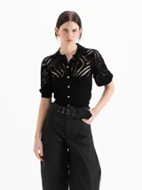 Cardigan negro tejido de textura liviana con puntos calados, escote con cuello polo, mangas cortas abullonadas y cierre frontal con botones dorados.