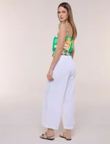 Pantalón crop de lino y rayón, con diseño wide leg de corte holgado, estampado tropical de hojas en tonos verde, azul y marrón sobre fondo blanco. Cuenta con pretina trasera elastizada y bolsillos delanteros.