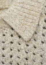 Jersey de punto calado con textura gruesa, cuello polo y terminaciones de canalé en puños y ruedo.