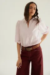 Blusa de algodón color rosado, con mangas cortas abullonadas, cuello mao y cierre frontal con botones.
