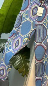 Pantalón cargo de tiro alto, color azul vibrante con estampado de círculos y estrellas en tonos morados y blancos. Presenta un calce ancho y holgado, con elástico ajustable en la parte trasera de la cintura y frunce en los tobillos que puede ajustarse o dejarse suelto.