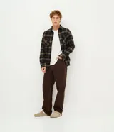 Pantalón masculino de corte baggy, confeccionado en sarga de algodón. Presenta un diseño holgado con costuras en contraste, cierre tradicional y cordón ajustable en la cintura.