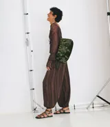 Pantalón de corte aladino confeccionado en viscosa y poliéster, con diseño de rayas verticales y acabado con leve transparencia. Presenta cintura alta, trabillas para cinturón y puños elásticos en el dobladillo.