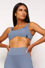 Top deportivo gris con escote cuadrado, breteles anchos y calce ajustado. Incluye forro interno y apertura para almohadilla removible.