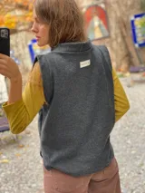 Chaleco de paño de lana gris con cuello alto y diseño sin mangas, de corte recto y holgado.