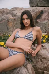Conjunto de bikini con estampado de cuadrillé azul marino y blanco, compuesto por un corpiño triangular con breteles regulables y espalda para atar, y una bombacha semivedetina con tiras laterales para atar.