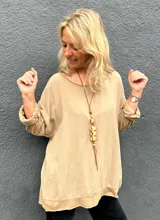 Blusa de corte holgado y diseño minimalista en color camel, con cuello redondo amplio y mangas tres cuartos con dobladillo.