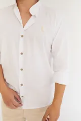 Camisa blanca de algodón con cuello mao, manga larga con puños abotonados y cierre frontal con botones de madera.