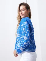 Chaqueta de algodón bordada, color azul con bordado floral blanco, con cuello a la base y escote en V, abertura central con botón.