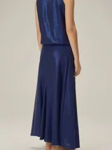 Falda larga azul marino de tejido satinado, con detalle de aplique floral en la cintura.