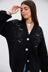 Saco de punto grueso color negro, con escote en V, cierre frontal de botones y mangas largas. Presenta detalles de bordado con lentejuelas y canutillos negros y plateados en la parte superior delantera.