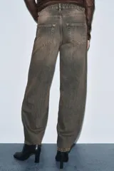 Jeans de tiro medio con diseño de pierna curva tipo barrel, confeccionados en denim con efecto lavado. Presentan cintura con trabillas, cierre frontal con cremallera y botón, y cinco bolsillos clásicos.