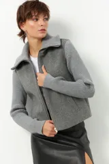 Tapado corto negro de paño con mangas y cuello tejidos, cierre metálico y bolsillos.