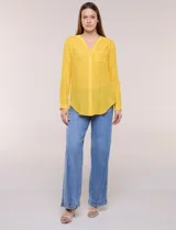 Blusa de calce relajado color salmón, confeccionada en tela liviana con textura sutil. Presenta escote en V con abotonadura frontal, bolsillo parche en el pecho, mangas largas regulables con presilla y ruedo con opción de anudar en el frente.