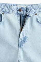 Jean de denim de algodón rígido, de color celeste claro, con tiro alto y pierna amplia de corte extraholgado. Presenta diseño clásico de cinco bolsillos, cierre frontal con cremallera y botón metálico.