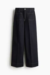 Jean de denim azul oscuro, de tiro alto y pierna ancha con corte holgado, con bolsillos de parche delanteros y costuras en contraste.