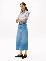 Falda midi de denim rígido celeste, corte recto de talle alto, con cinco bolsillos, abertura frontal y cierre de cremallera con botón.