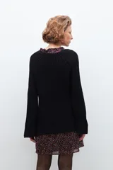 Sweater negro de tejido de punto grueso, con escote en V y detalle de cinta estampada floral en el borde del escote.