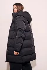 Tapado negro largo con capucha, diseño capitoneado y cierre frontal con botones dorados.