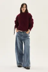 Polera de tejido de punto con diseño de ochos y detalles de tientos en contratono en las mangas. Presenta cuello alto y corte cropped.