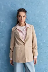 Blazer de corte sastrero con silueta relajada, solapas tradicionales, cierre frontal de un botón y bolsillos de vivo.