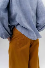 Pantalón de gabardina de algodón color negro, con calce barrel, cintura media baja, recortes de diseño y detalle de botones en el ruedo para ajustar el volumen.