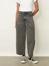 Jean de corte wide leg en color gris con efecto lavado. Presenta tiro medio, cierre frontal con botón y bolsillos laterales y traseros.