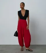 Pantalón de sastrería color rojo, modelo aladín con cintura alta, pinzas frontales y bajo ajustado. Confeccionado en tejido de viscosa con elastano.