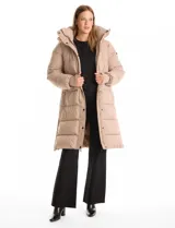Campera puffer larga de abrigo marca BCBG Maxazria, color beige. Cuenta con capucha desmontable, cuello alto envolvente, cierre frontal bidireccional con solapa de botones a presión, bolsillos laterales, puños internos elastizados y tajos laterales con cierre en el bajo.