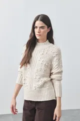 Polera de tejido de punto color marrón, con cuello alto y diseño de textura con relieves y trenzas. Posee mangas largas con puños acanalados.