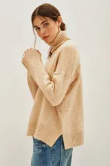 Polera de cuello alto en color beige, confeccionada en tejido de punto suave. Presenta un diseño clásico de manga larga con puños acanalados.