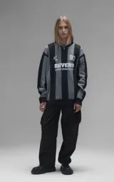 Sweater de punto con diseño a rayas verticales en negro y gris, cuello redondo y mangas largas. Presenta un estampado gráfico frontal con estilo deportivo retro que incluye el texto 'Ravers' y el número '90'. Cuenta con terminaciones en punto rib en cuello, puños y ruedo.