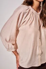 Blusa de manga larga con diseño a rayas verticales, cuello redondo con pequeña abertura frontal abotonada y mangas con puños elásticos.