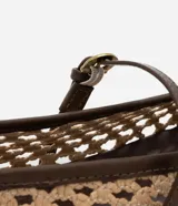 Zapatilla tipo bailarina con capellada tejida con efecto rafia color beige, punta redonda, tira fina marrón con hebilla y suela marrón.