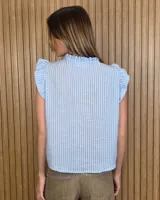 Musculosa a rayas verdes y blancas, con cuello alto fruncido, cierre frontal con botones y volados en los hombros.