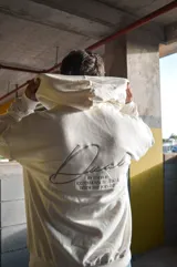 Hoodie canguro blanco de diseño oversize, con capucha, bolsillo frontal tipo koozban y sutil bordado monocromático en el pecho.