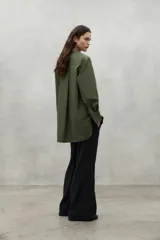 Camisa de manga larga color verde oliva, con cuello clásico, botones frontales y un bolsillo de parche en el pecho. Presenta un corte holgado.