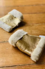 Guantes sin dedos confeccionados en cuero negro con ribetes de corderito al tono en los extremos. Presentan un diseño abrigado y una pequeña etiqueta de marca en el lateral.