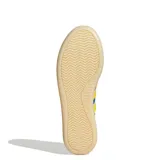 Championes urbanos Adidas modelo Barreda Decode, con diseño inspirado en el calzado de fútbol retro. Presentan una combinación de colores azul y violeta con las icónicas tres tiras en amarillo. Cuentan con puntera en forma de T, refuerzos de gamuza y una suela de goma translúcida.