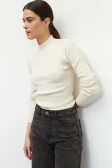 Polera de tejido de punto acanalado en color crema, con cuello alto y manga larga, de ajuste ceñido al cuerpo.