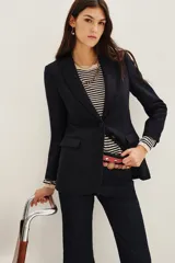 Saco de corte sastrero en color azul marino, con solapas clásicas, cierre frontal de un botón y bolsillos laterales con solapa. Presenta una estructura entallada con hombreras.