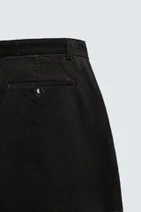 Pantalón de corte carrot fit confeccionado en tejido de mezcla de algodón. Presenta bolsillos frontales, bolsillos traseros de vivo y cierre frontal con cremallera y botón.