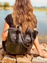 Mochila negra de cuero convertible en bolso de mano o bandolera. Tiene compartimento para laptop, bolsillos exteriores y correas ajustables y extraíbles.