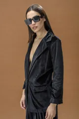 Blazer de terciopelo negro con solapas clásicas, cierre frontal con un botón y bolsillos laterales con solapa.