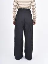 Pantalón de vestir negro de corte wide leg, con pinzas frontales y cintura alta.