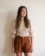 Blusa de algodón con estampado de rayas multicolor, cuello alto con volado, mangas abullonadas con puños fruncidos y cuerpo con frunces elastizados.