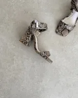 Sandalia de taco cuadrado alto, con diseño de punta cuadrada, tira delantera ancha y tira ajustable en el tobillo con hebilla metálica.